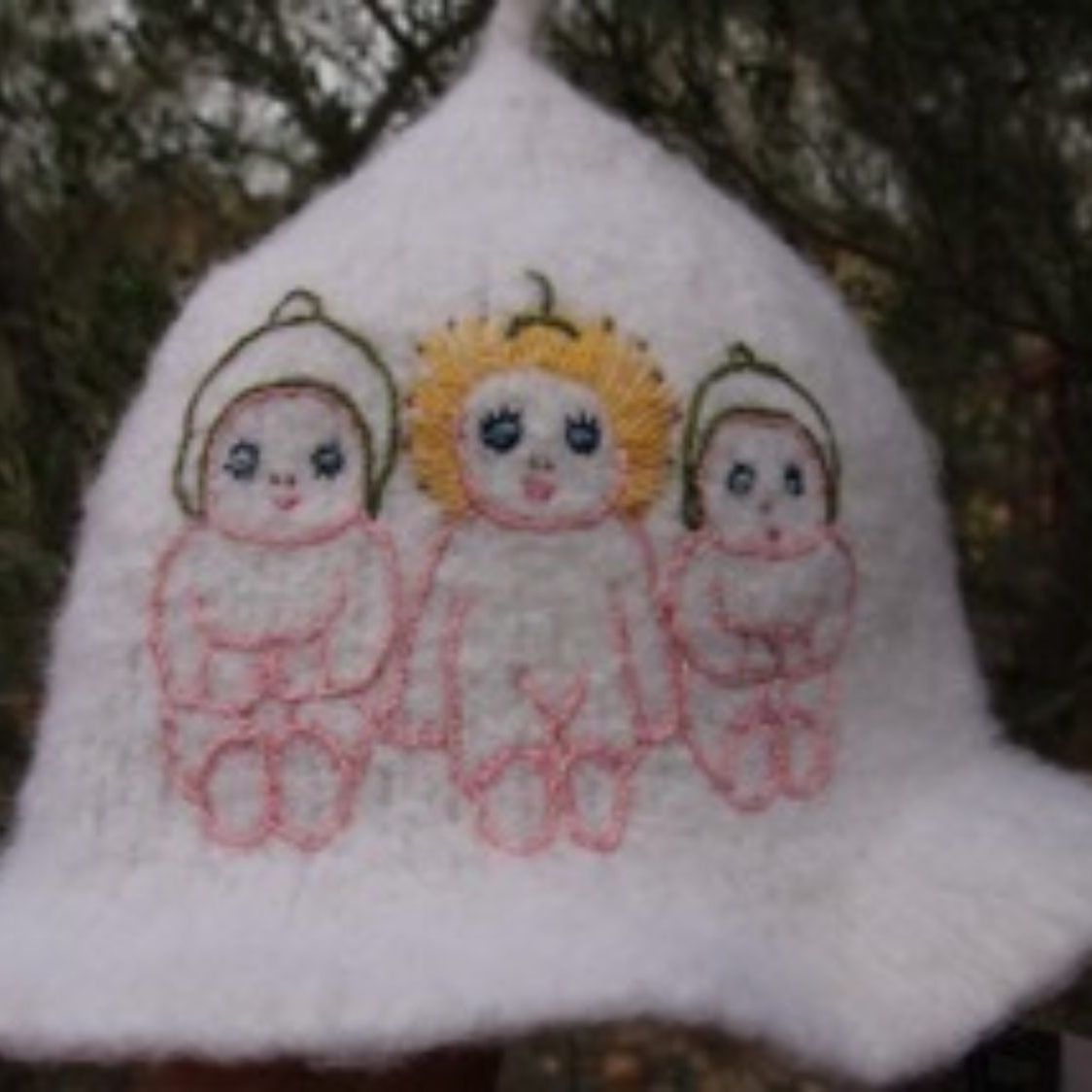 A white hat with three dolls embroidered on it