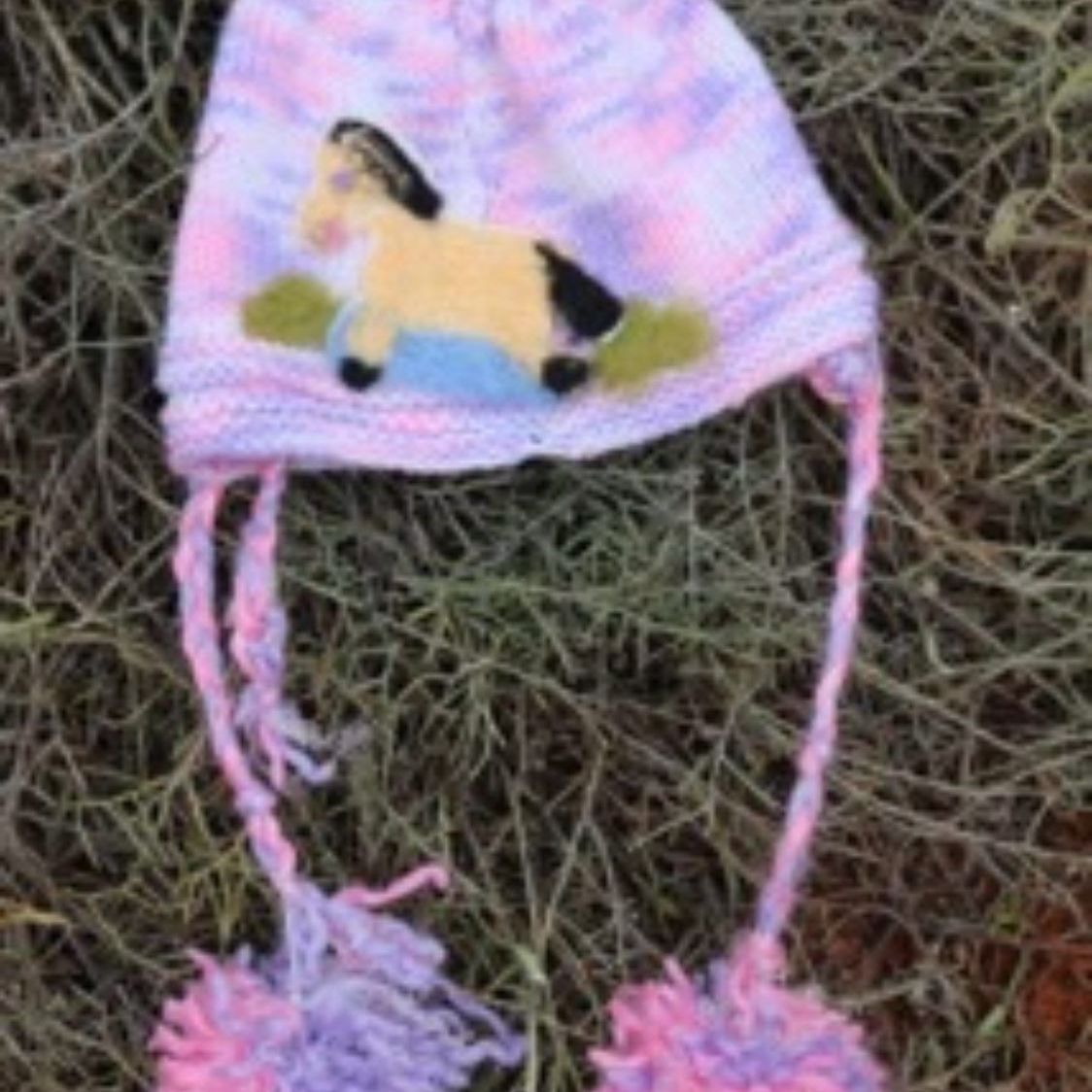 A hat with a horse on it is sitting on a pile of hay.