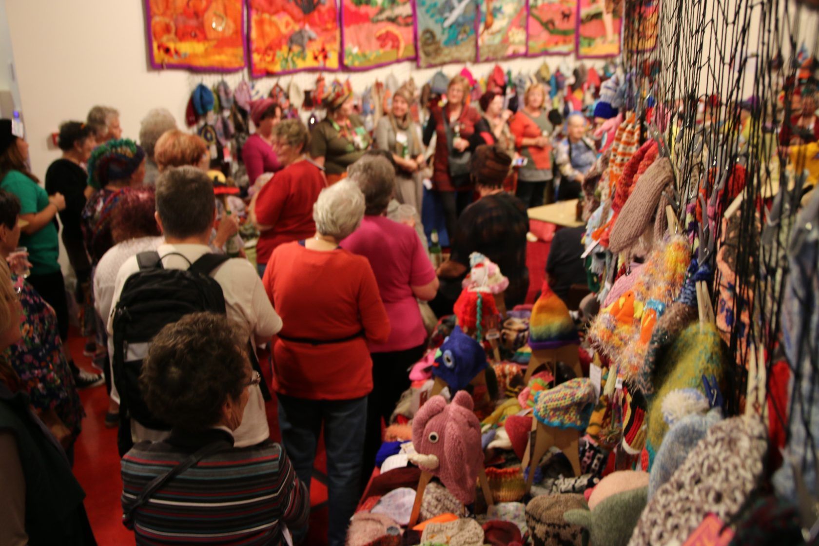 A large group of people are standing in a room filled with lots of stuffed animals.