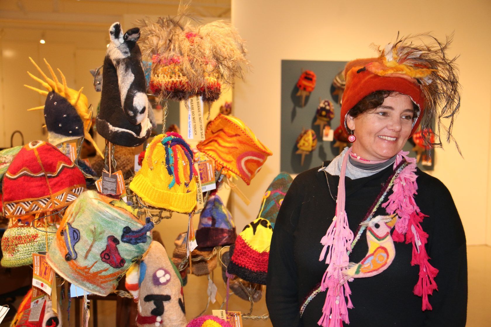 A woman is standing in front of a display of hats.