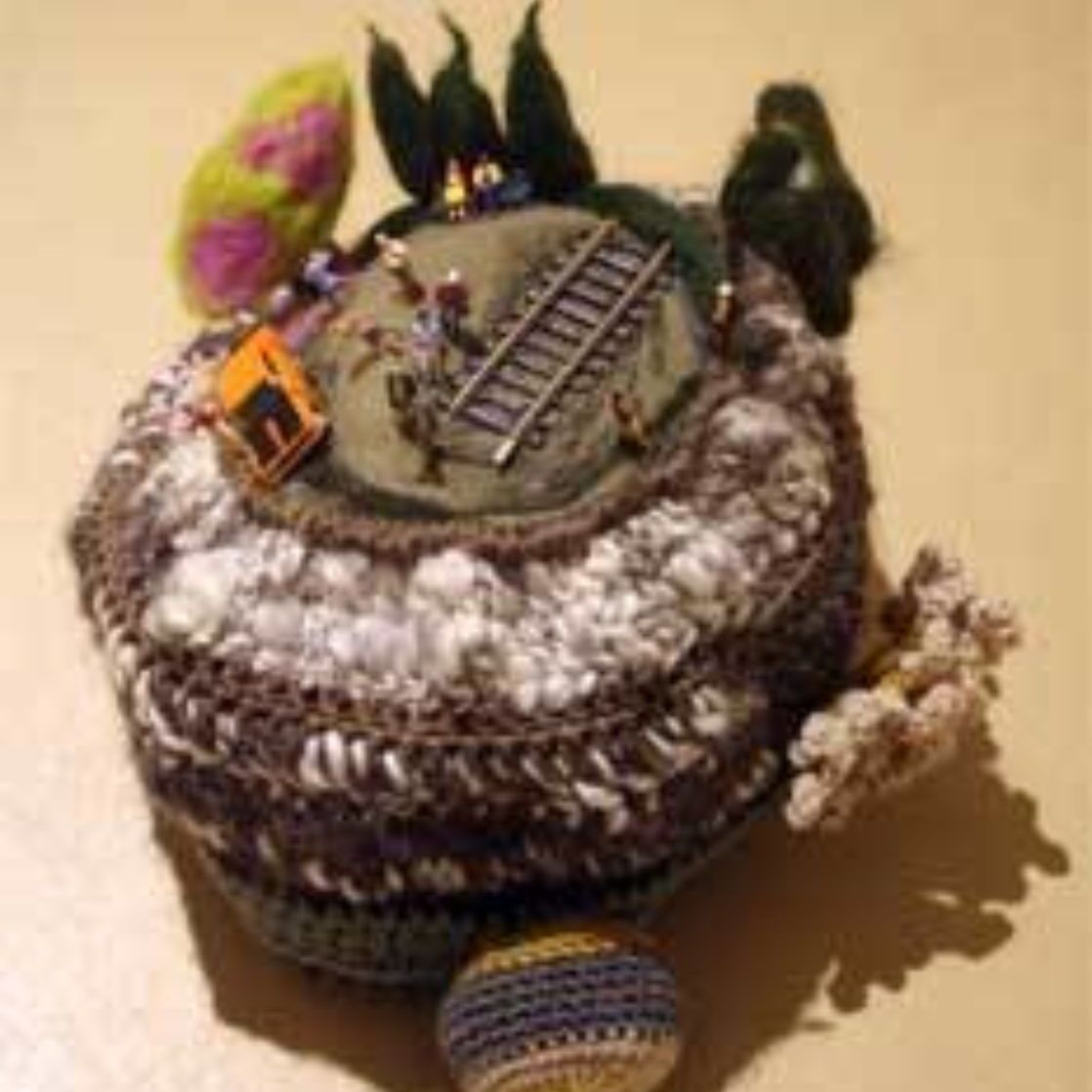 A crocheted hat with a train on top of it