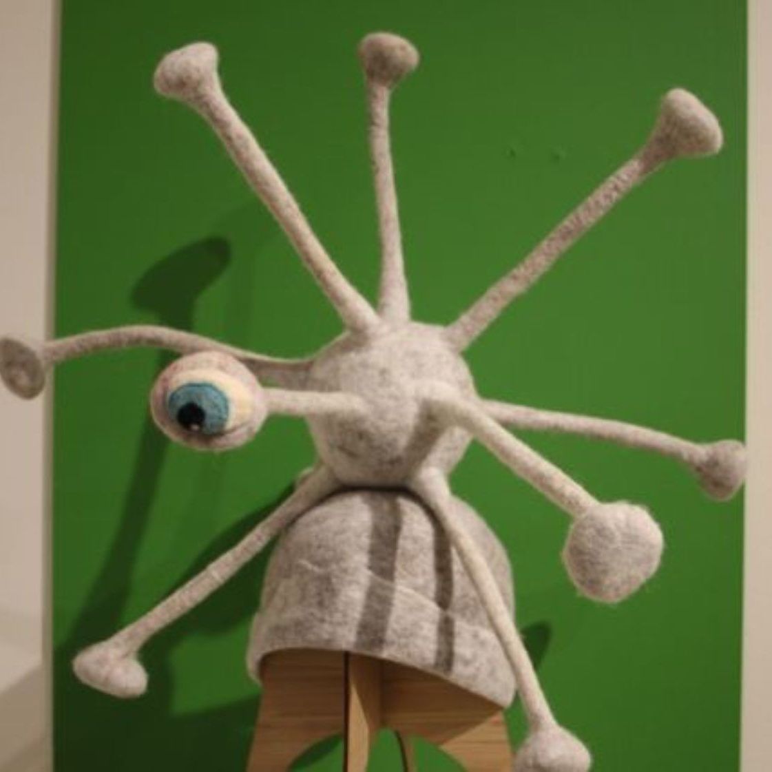 A stuffed animal with a blue eye and many tentacles on a green background