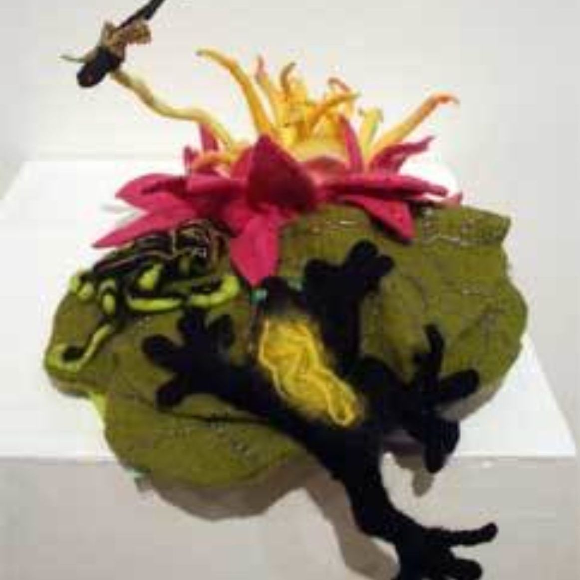 A frog is sitting on a leaf with a flower in the background.