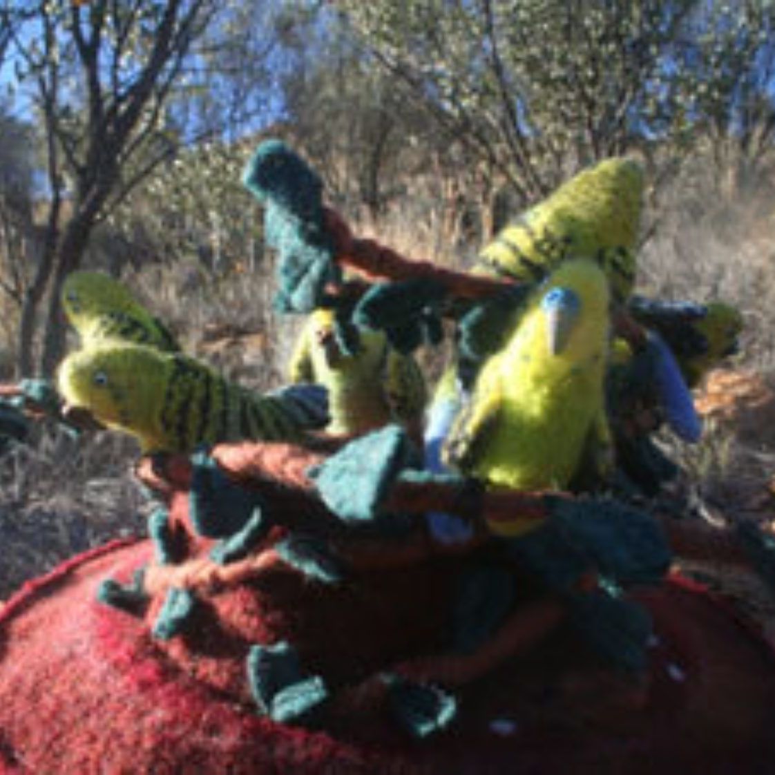 A bunch of stuffed birds are sitting on top of a red blanket.