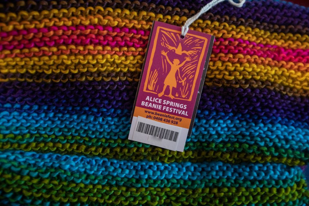 A colorful knitted blanket with a tag that says peace avenue annual festival