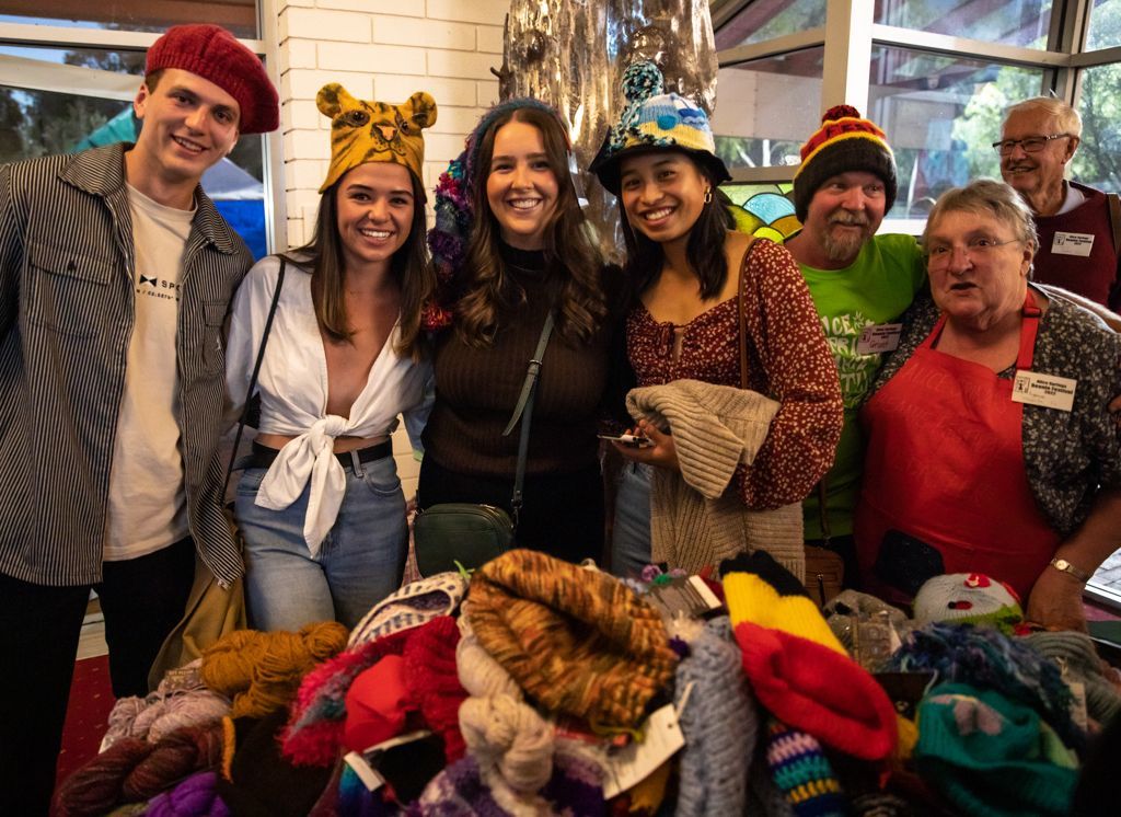 A group of people are posing for a picture in front of a pile of hats.