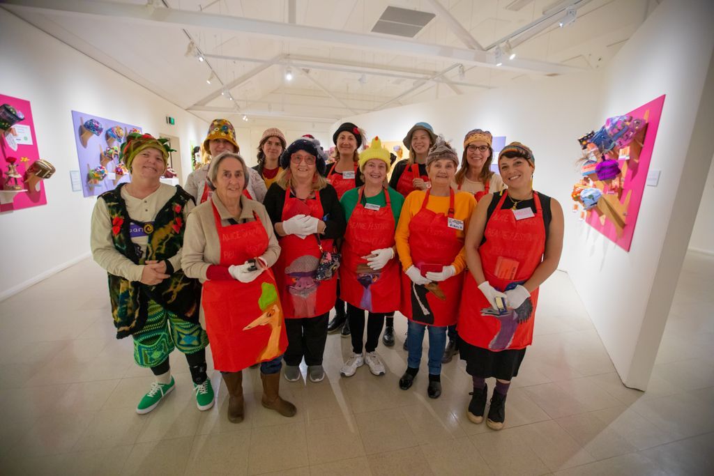 A group of women are posing for a picture in an art gallery.