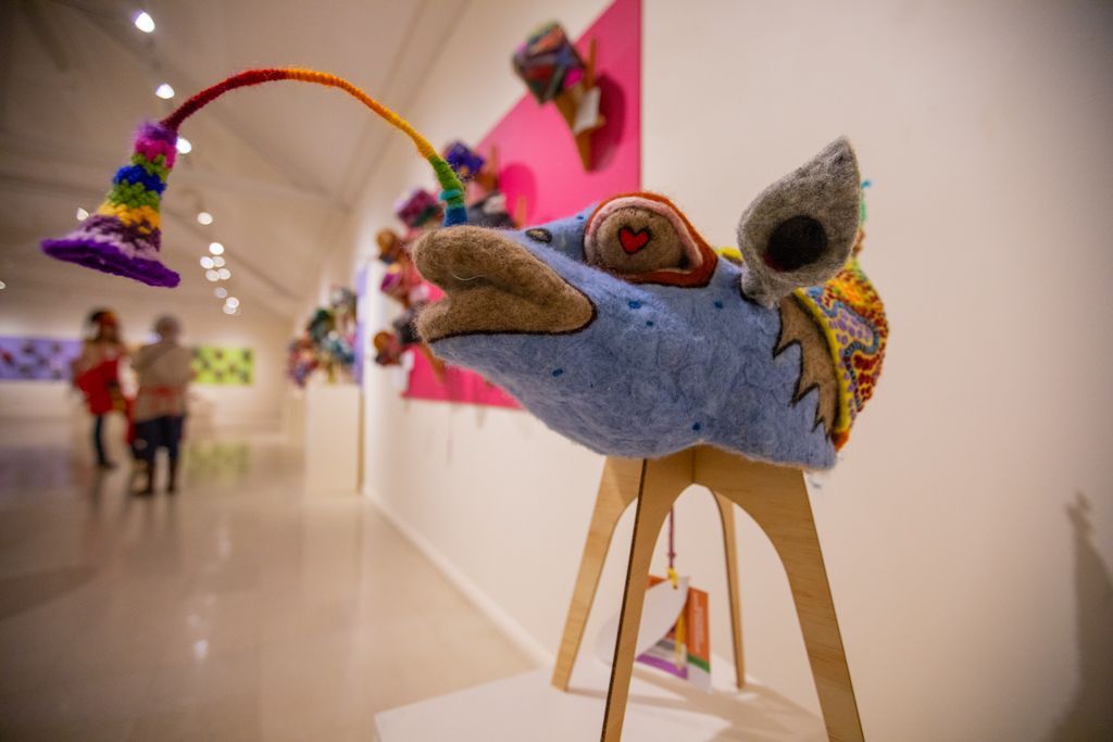 A stuffed animal is sitting on a wooden stool in a museum.