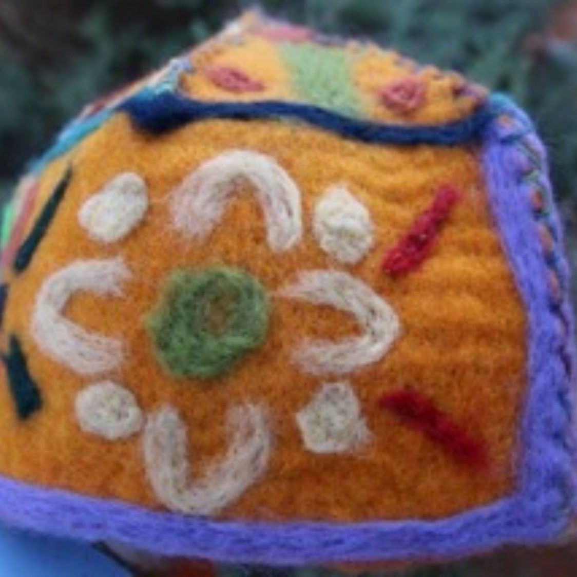 A close up of a knitted object with a flower on it