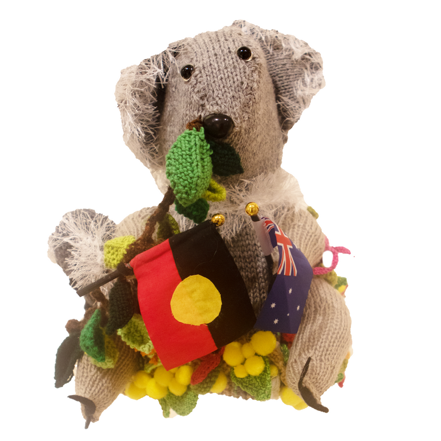 A stuffed koala bear with a red white and blue flag around its neck