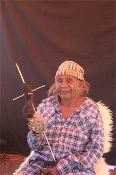 A woman in a plaid shirt is sitting in a chair holding a feather.
