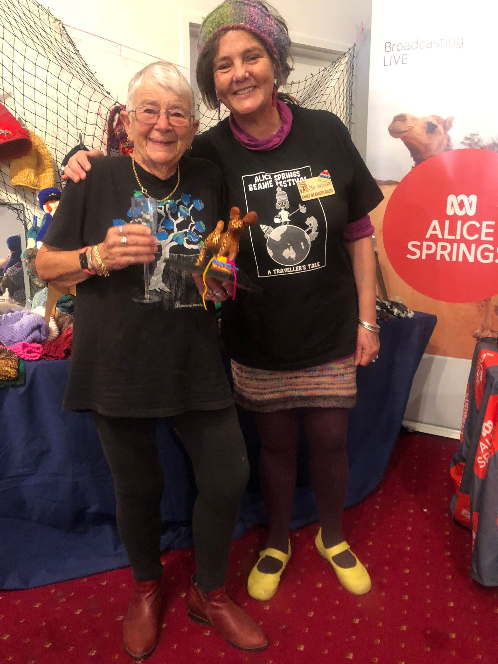 Two women are posing for a picture in front of a sign that says alice spring