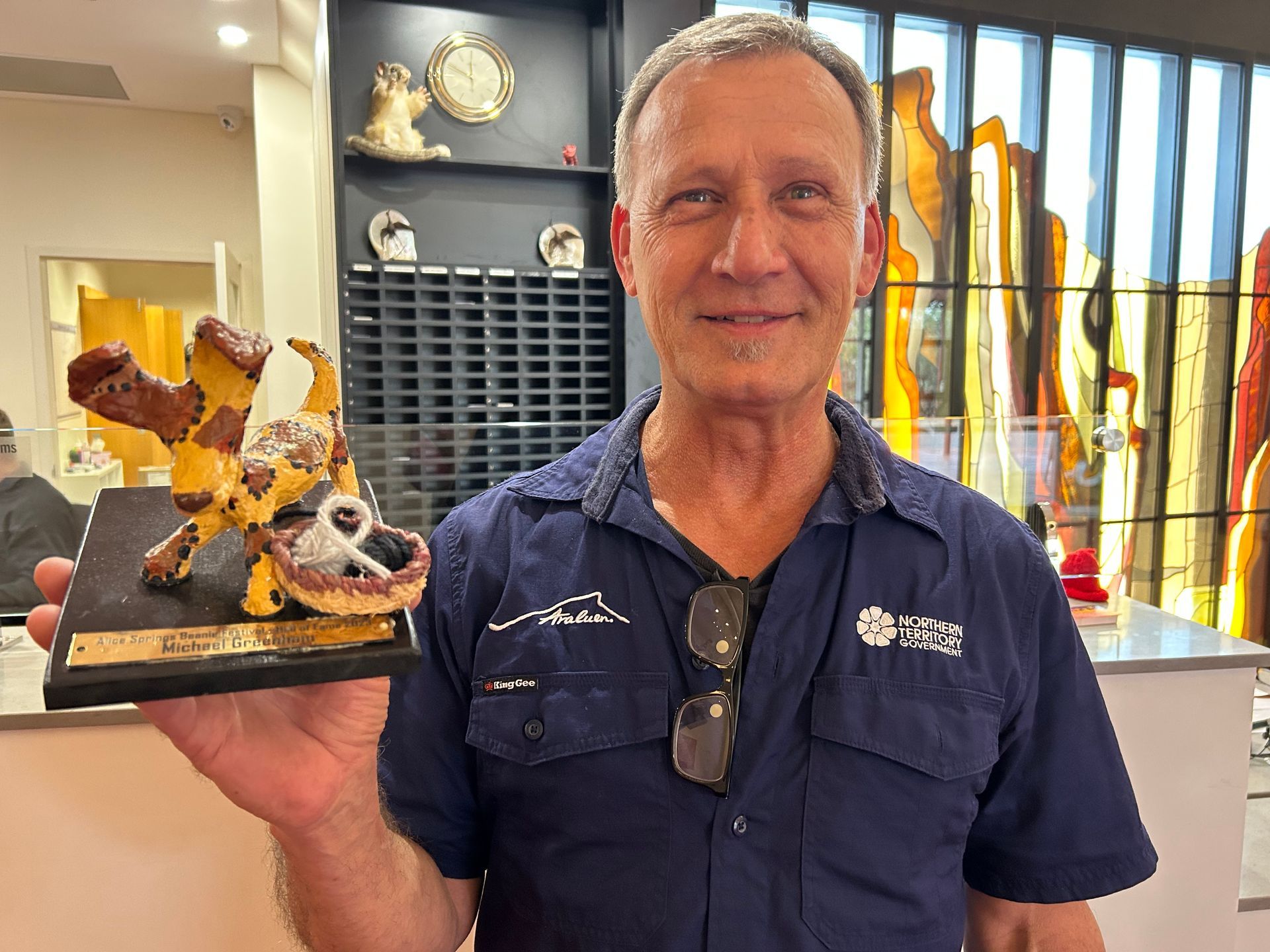 A man in a blue shirt is holding a statue of a camel.