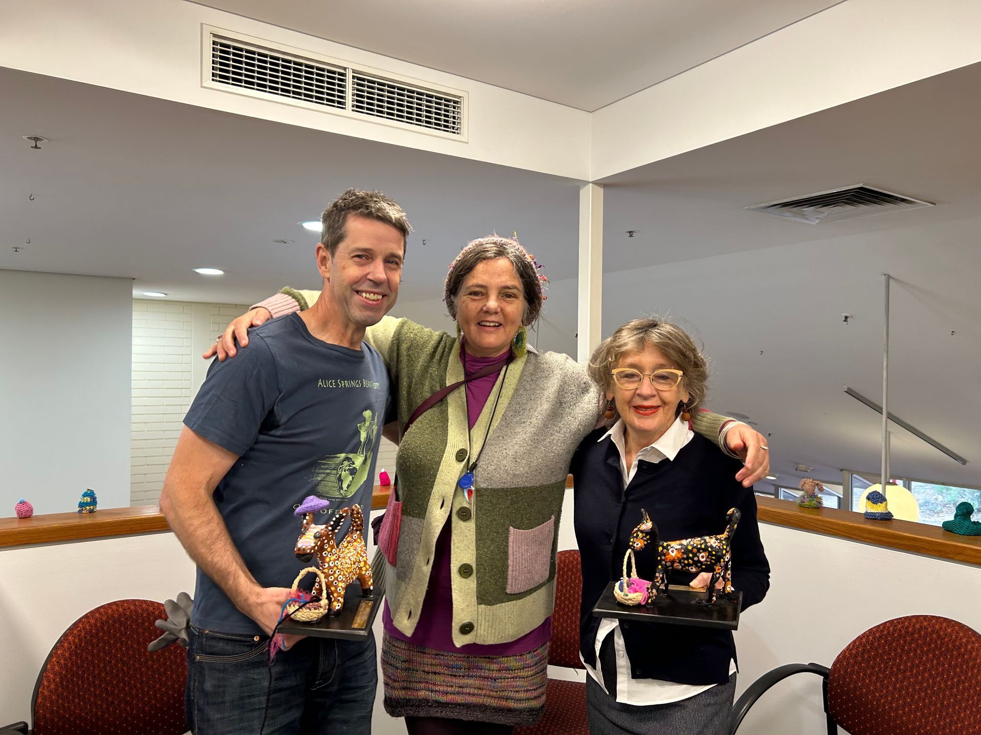 A man and two women are posing for a picture in a room.