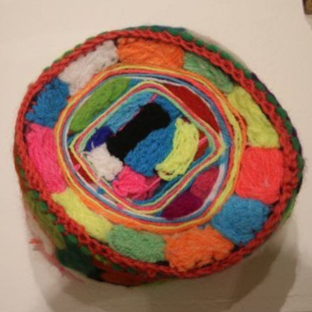 A colorful ball of yarn is sitting on a white surface