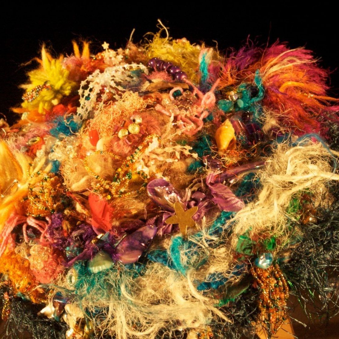 A close up of a pile of colorful yarn on a black background.