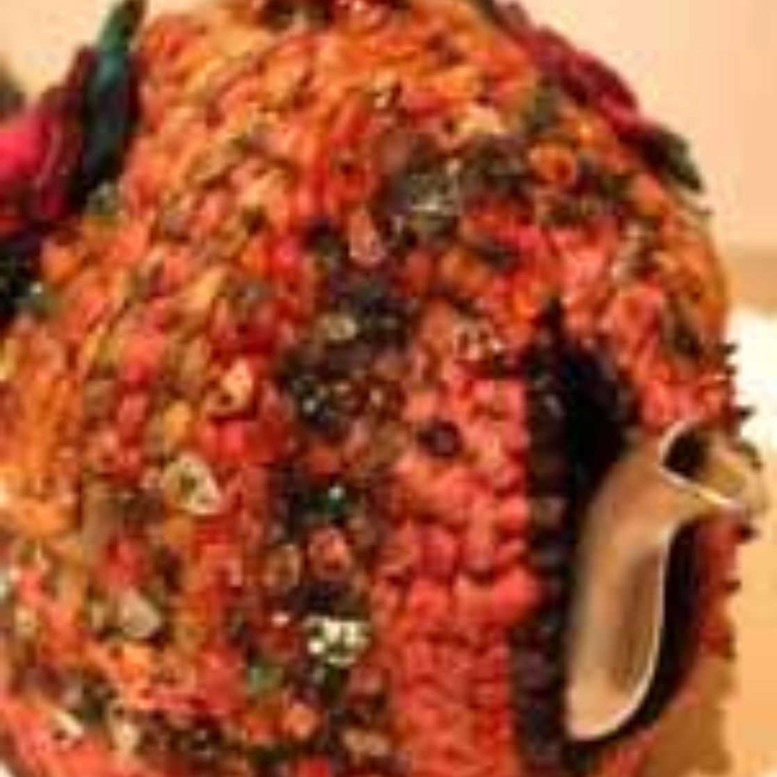 A close up of a teapot covered in flowers on a table.