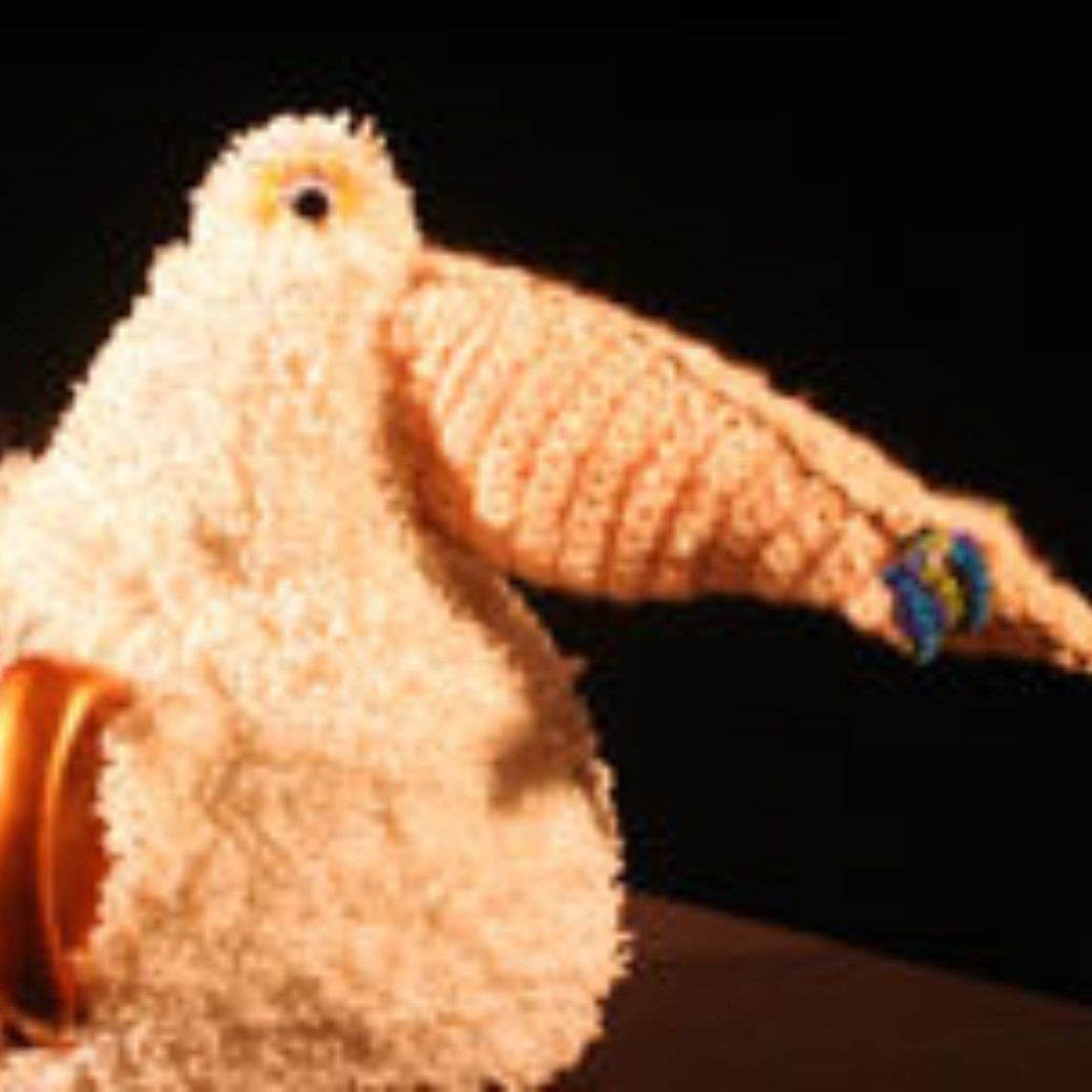 A stuffed animal is sitting on a table with a ribbon around its neck.