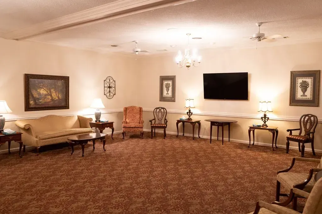 A spacious room with chairs and couches, likely a waiting area with a TV and wall art.