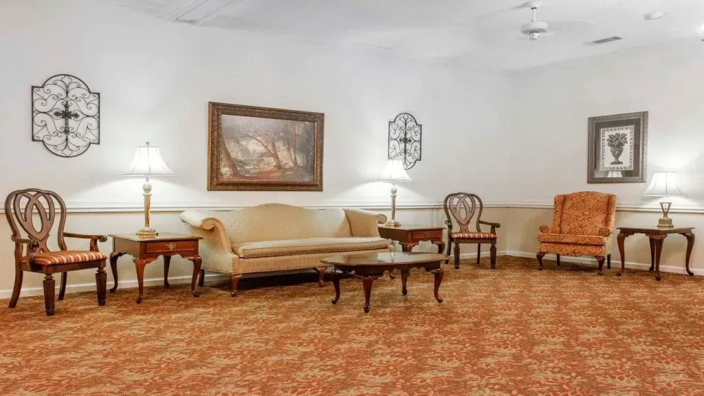 A formal living room with antique furniture, warm lighting, and patterned carpet.