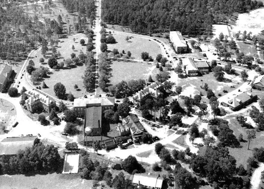 Aerial view of a campus with multiple buildings, trees, and roads.