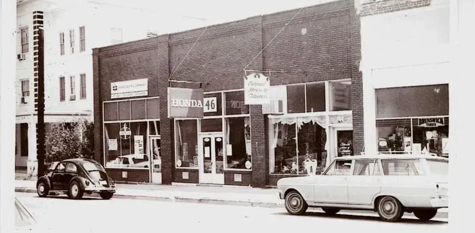 Street scene with brick buildings, storefronts, cars, and a black Beetle.