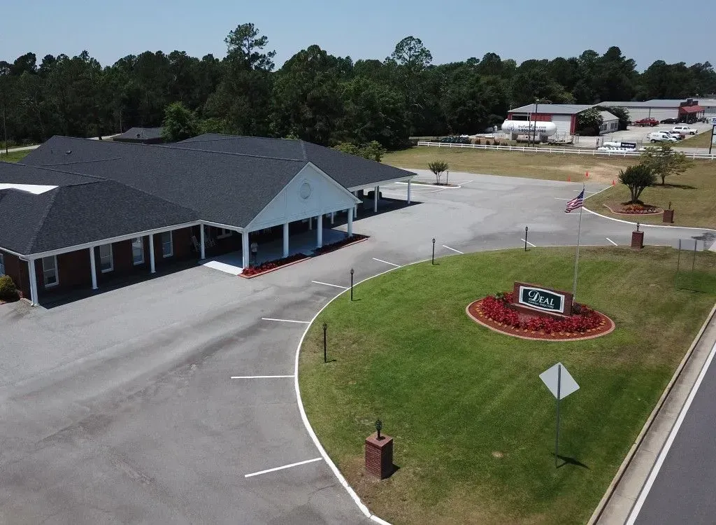 A single-story brick building with a dark roof and a lawn with a sign.