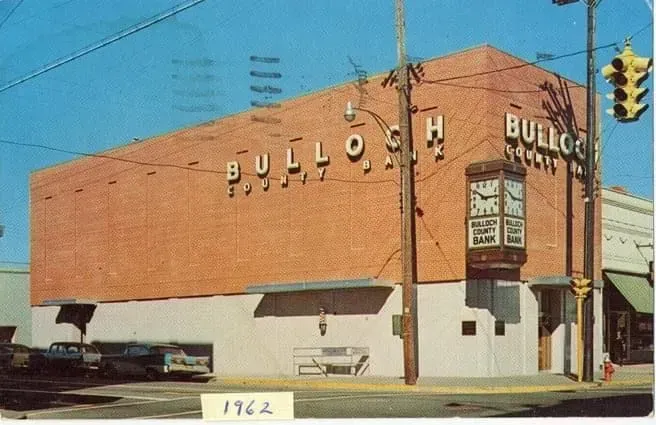 Bulloch's furniture store in Statesboro, Georgia. Red brick building with large sign and clock. 1962.