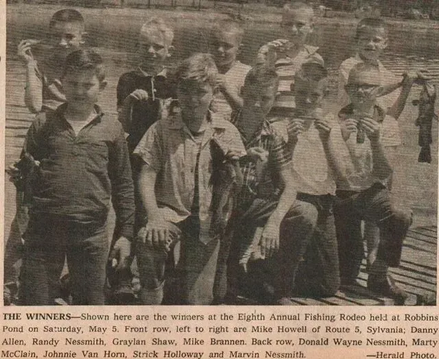 Group of boys with fish, winners of fishing rodeo, posing outdoors.