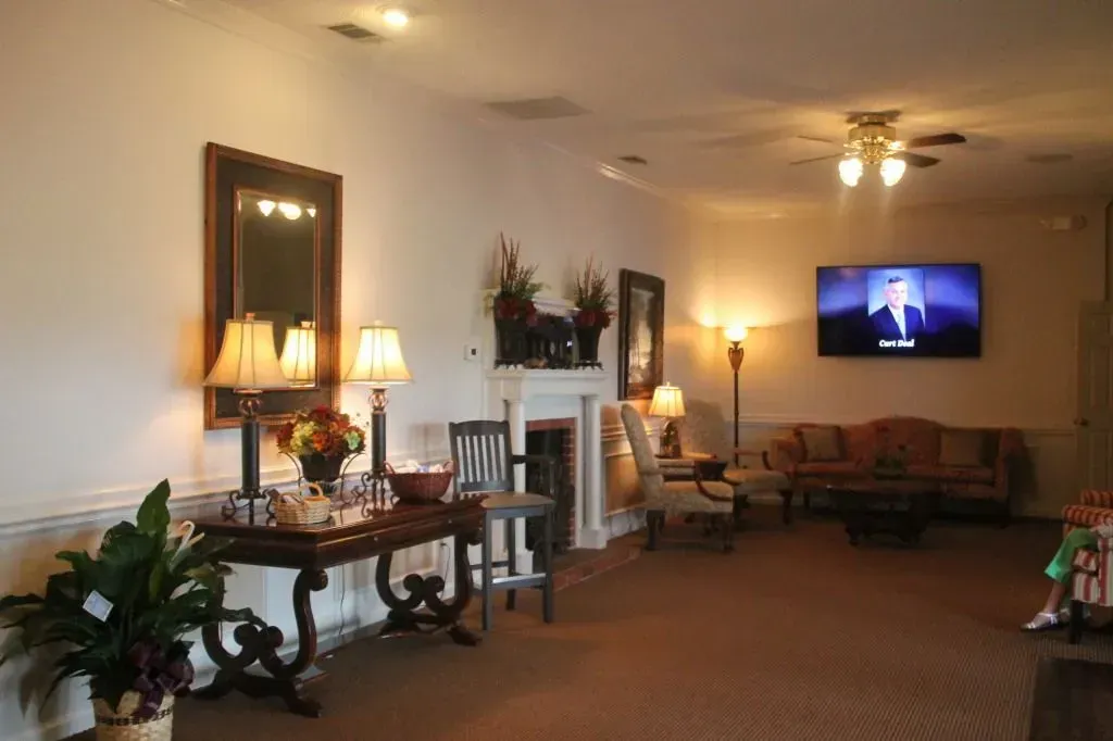 A well-lit waiting room with seating, a fireplace, and a TV showing a person speaking.