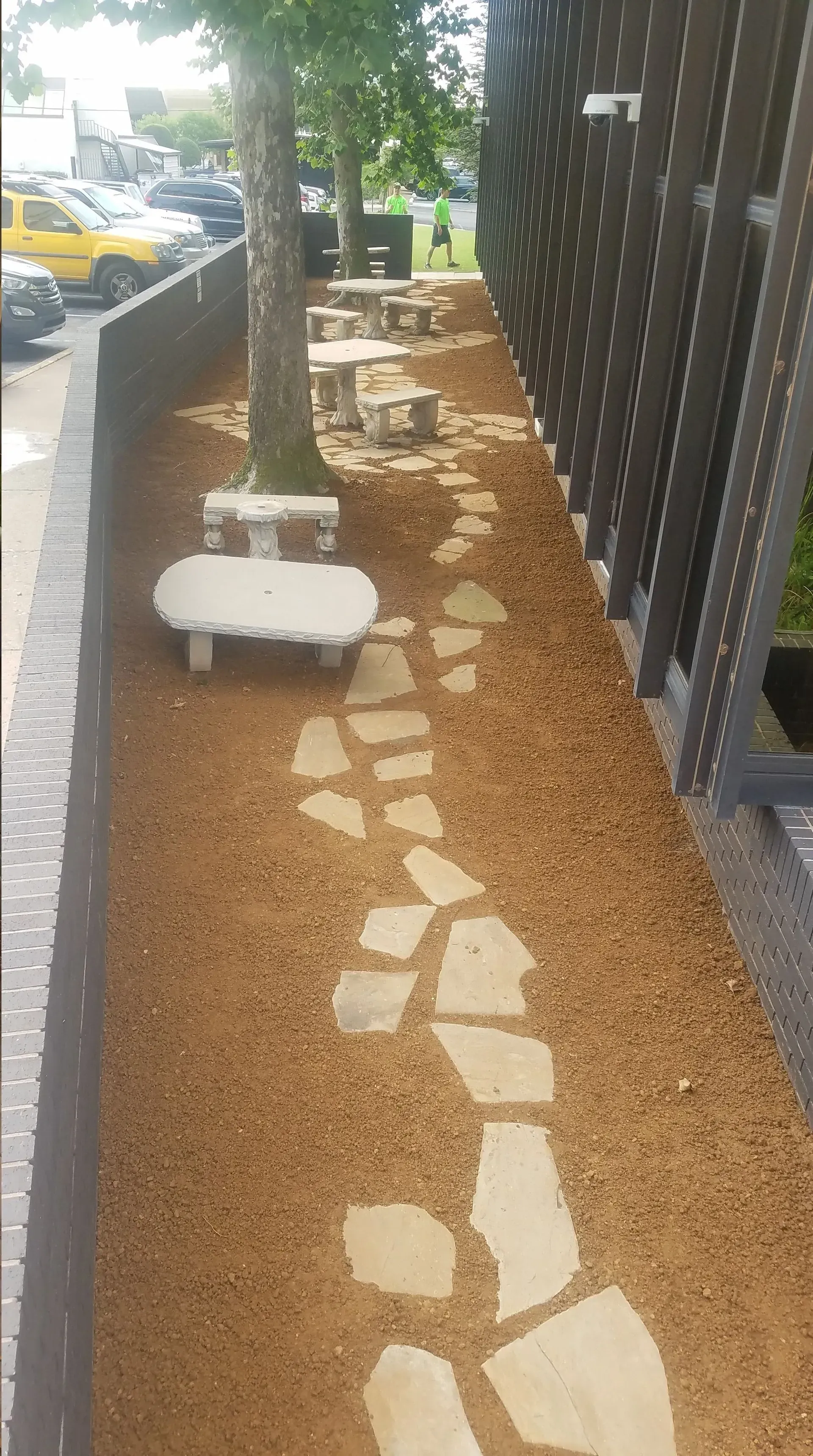 Pathway with stone slabs and benches in a gravel-covered landscaped area, next to a building.