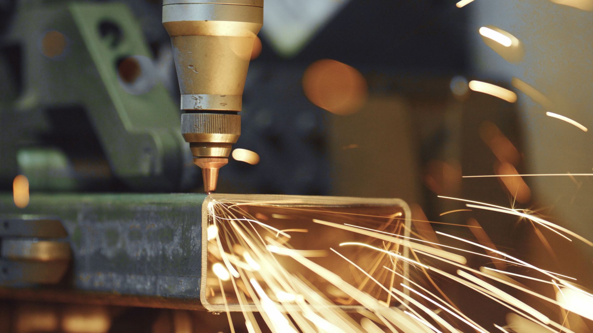 Laser cutter cutting metal, with bright sparks flying.