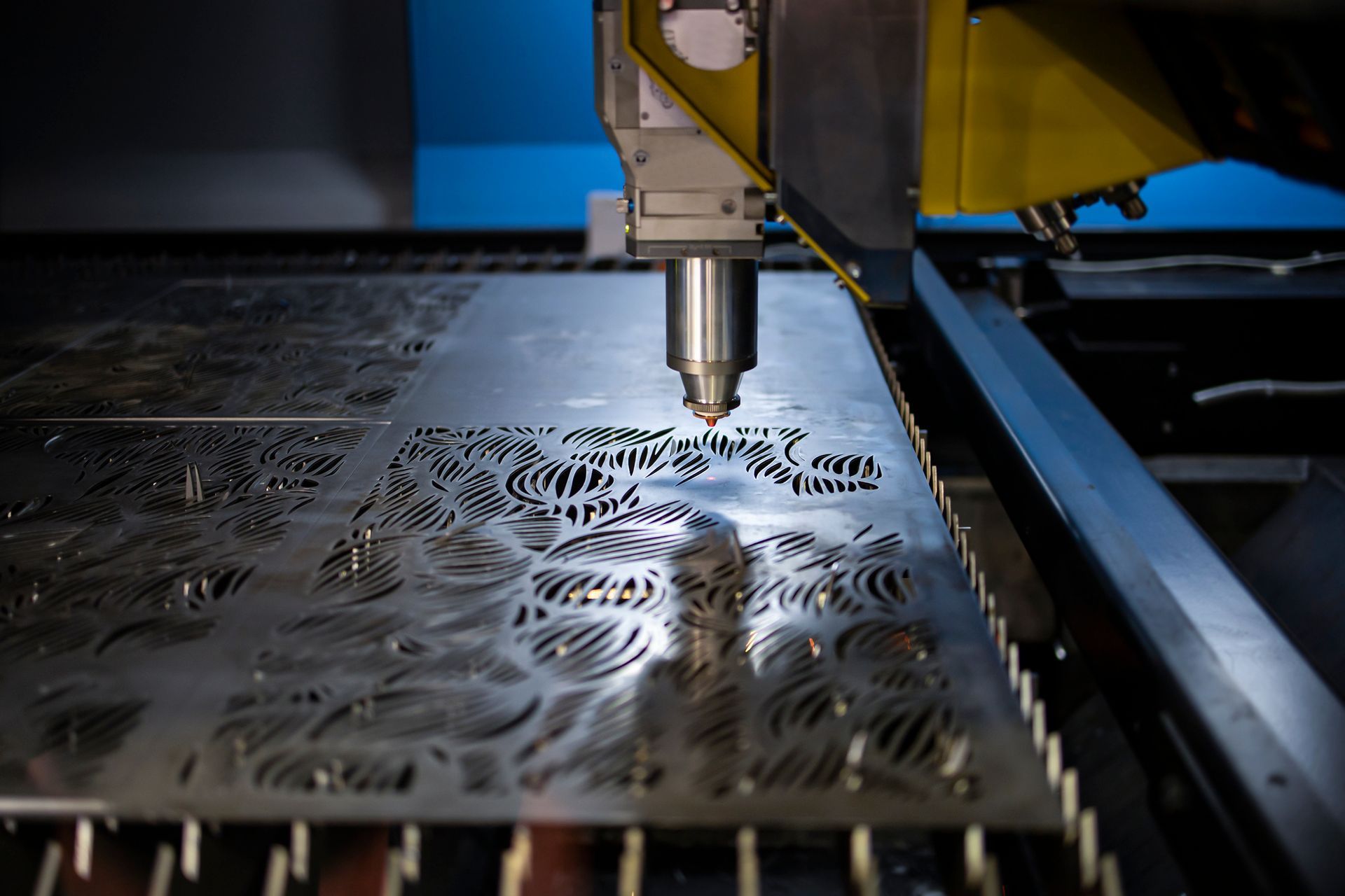 Laser cutter cutting intricate design into metal sheet.