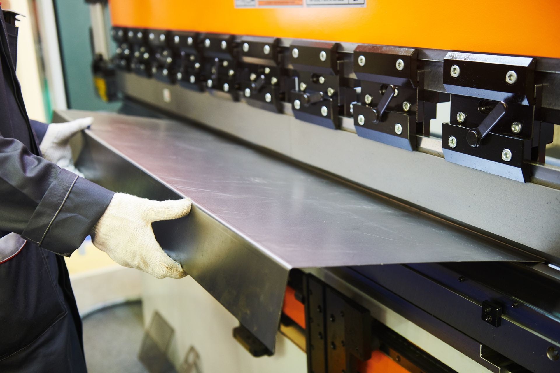 Close-up of a worker using a bending machine for flat sheet metal. Close-up of a worker using a bending machine for flat sheet metal.
