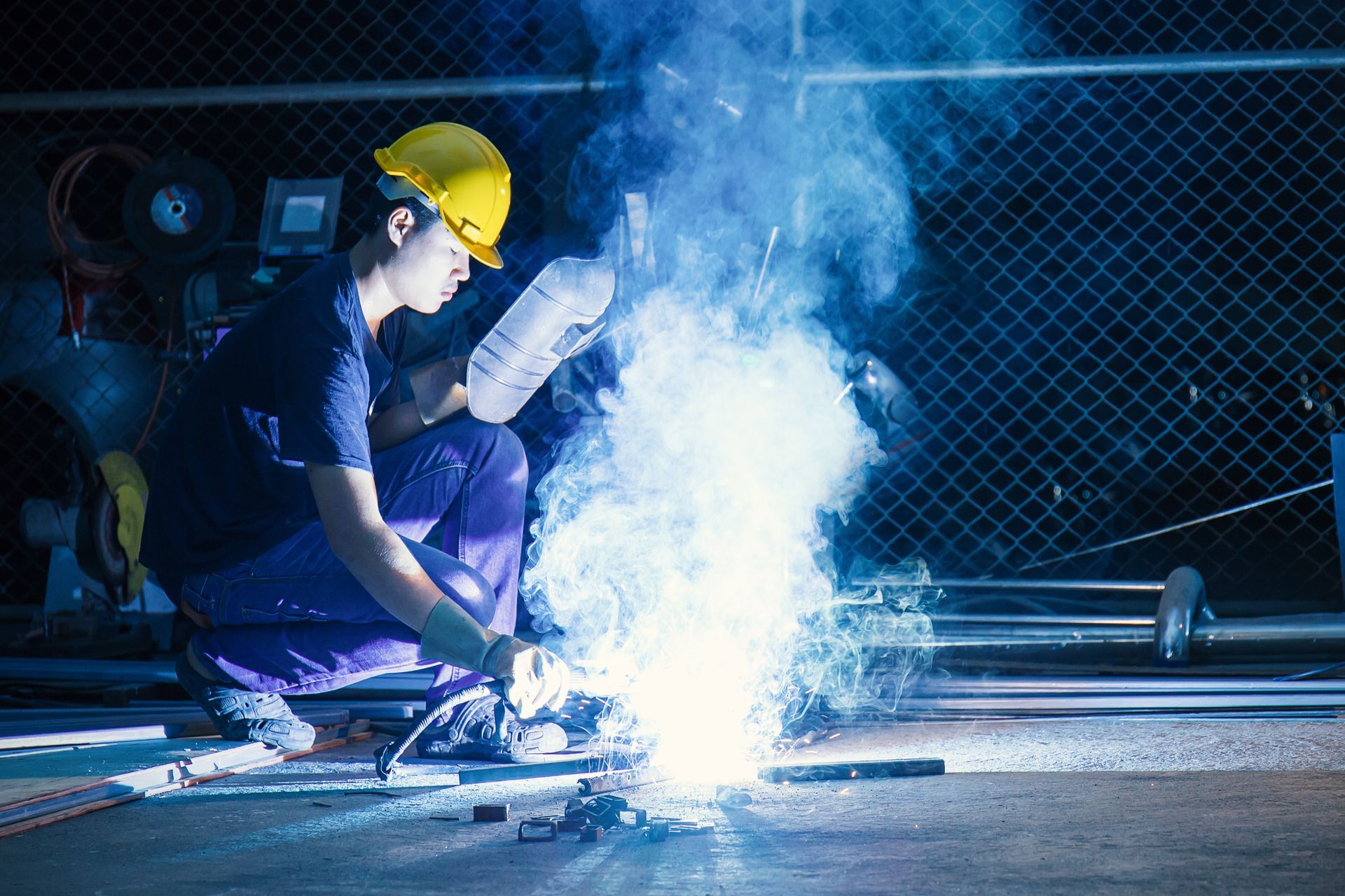 Worker while doing a welding with an arc welder with smoke Worker while doing a welding with an arc welder with smoke