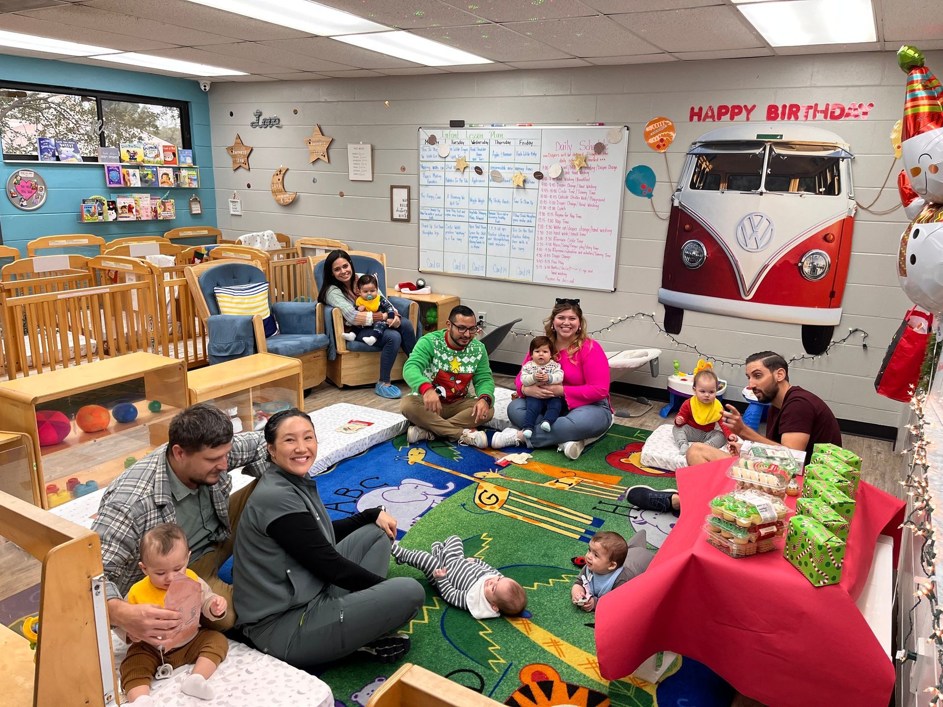 A group of people are sitting on the floor in a room with babies.