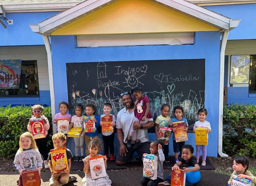 A group of children are posing for a picture in front of a blue building.