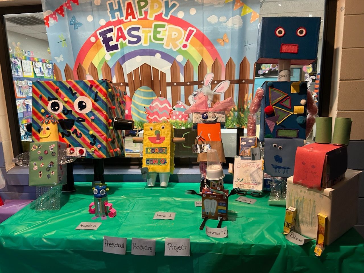 A group of robots made out of cardboard boxes are sitting on a table.