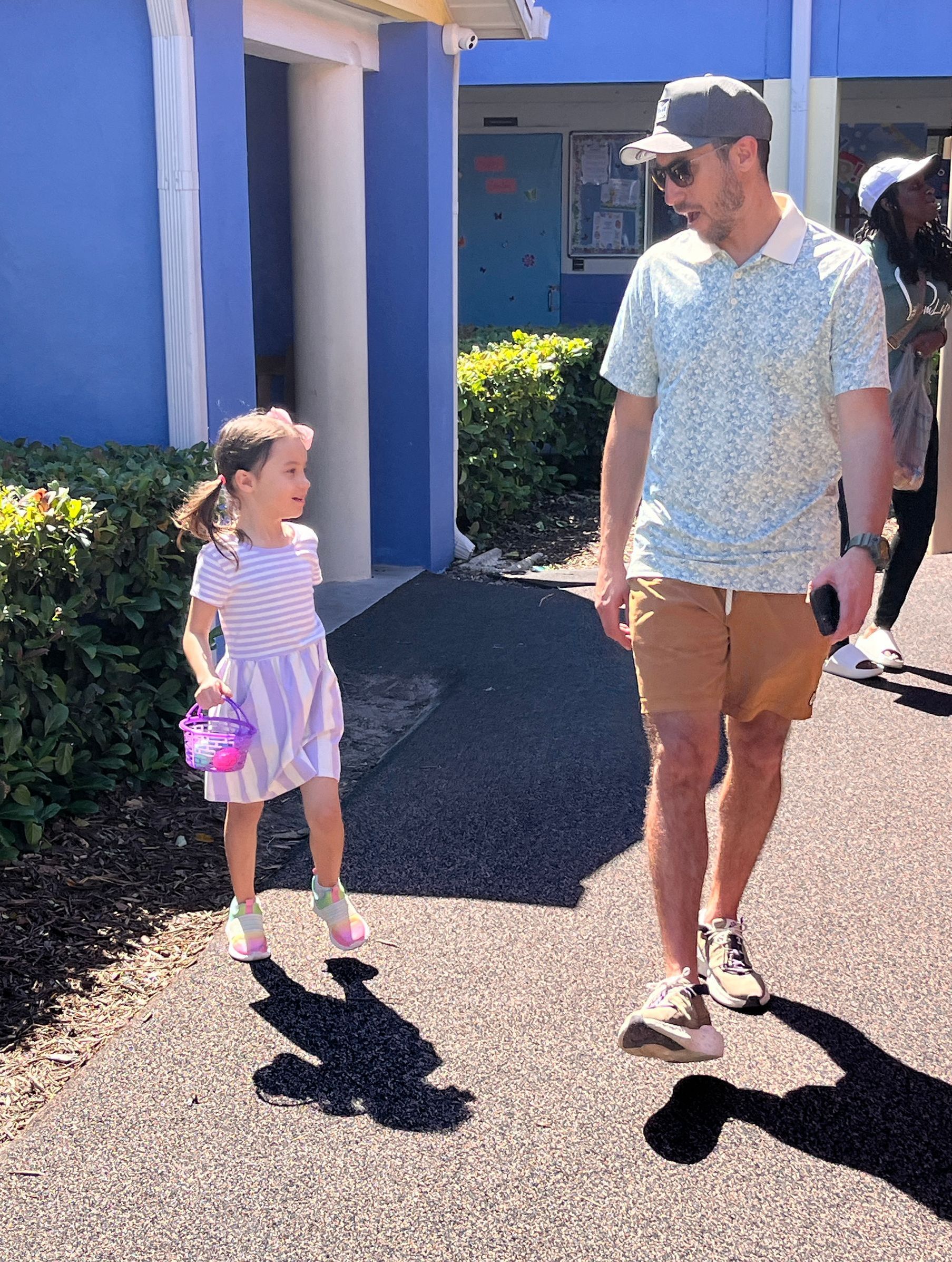 A man and a little girl are walking down the street.