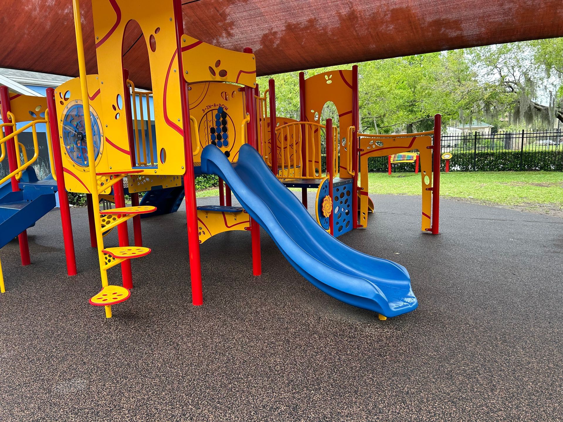 A colorful playground with a blue slide and stairs in a park.
