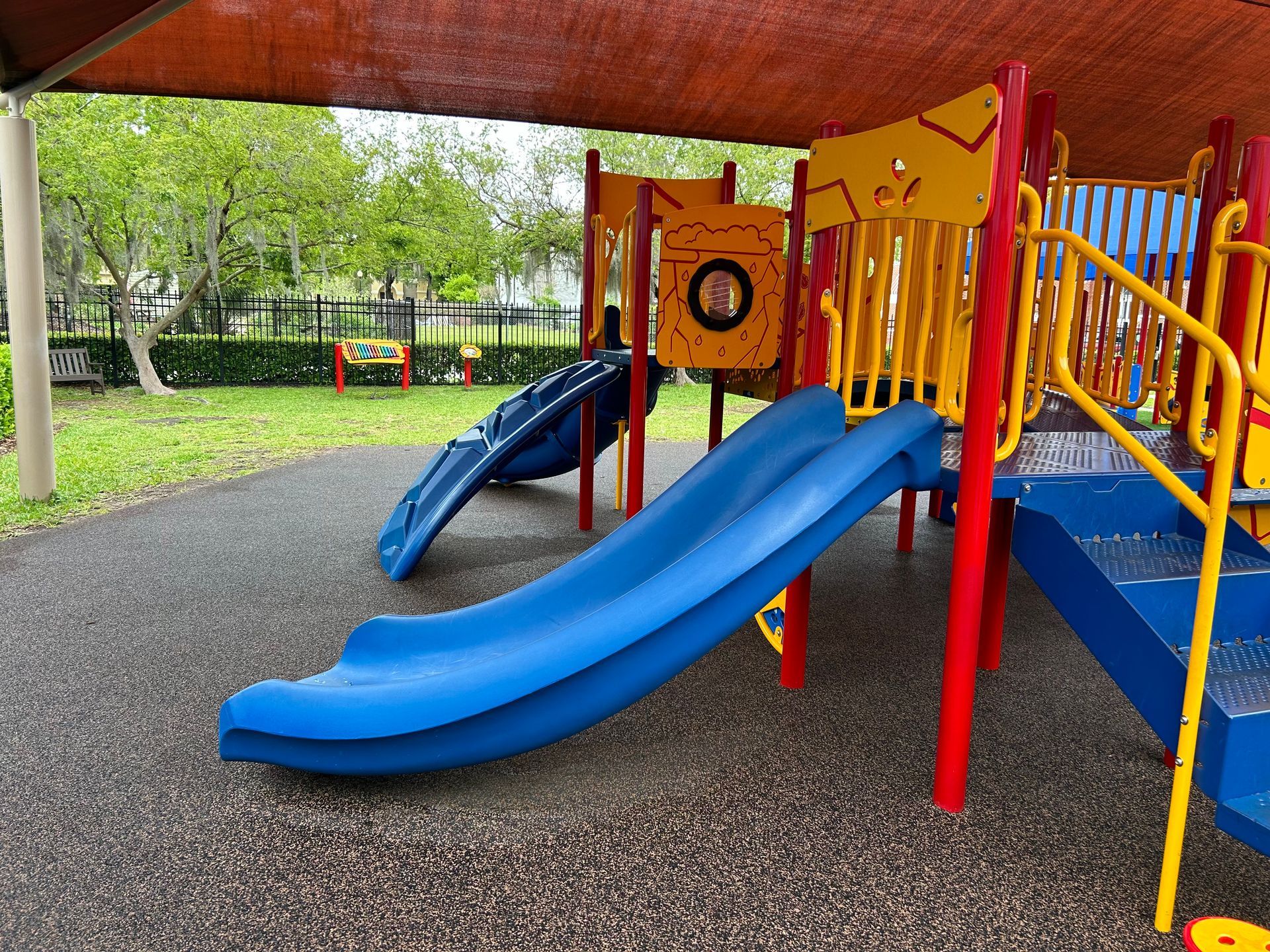 A playground with a blue slide and a yellow slide