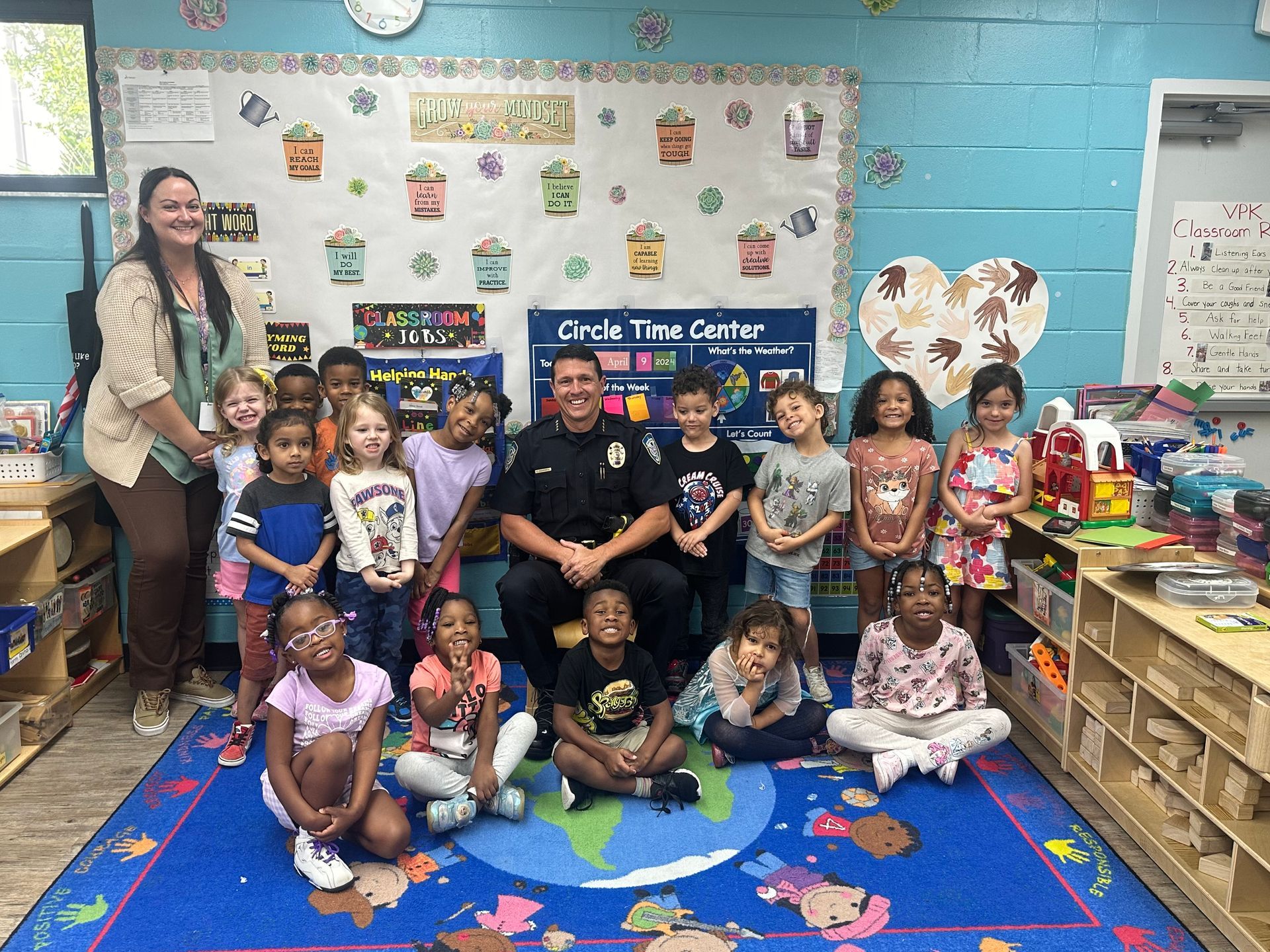 A group of children are posing for a picture with a police officer in a classroom.