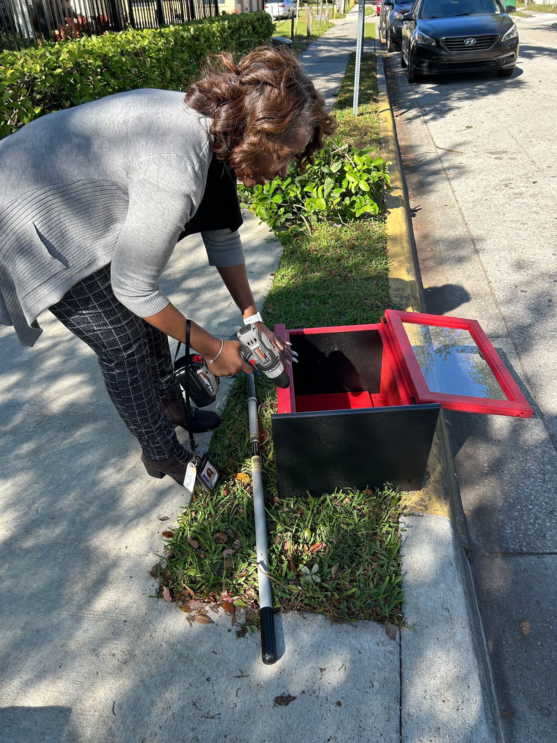 A woman is standing next to a red box on the sidewalk.