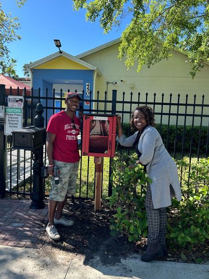 A man and a woman are standing next to a red box.