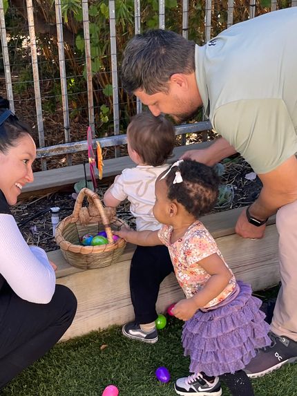 A family is playing with easter eggs in a garden.