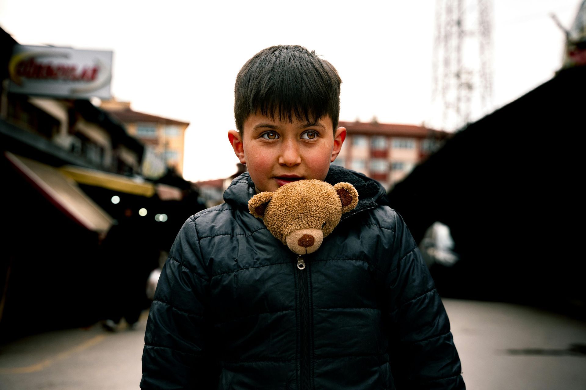 A young boy is holding a teddy bear in his mouth.