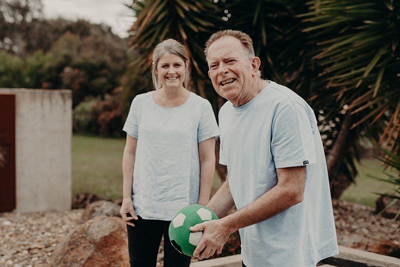 A man and a woman are standing next to each other holding a soccer ball.