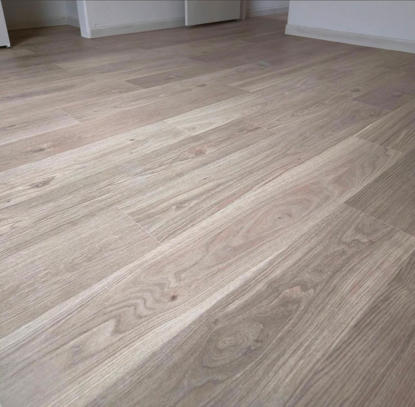 Empty room with light wood flooring and white walls.
