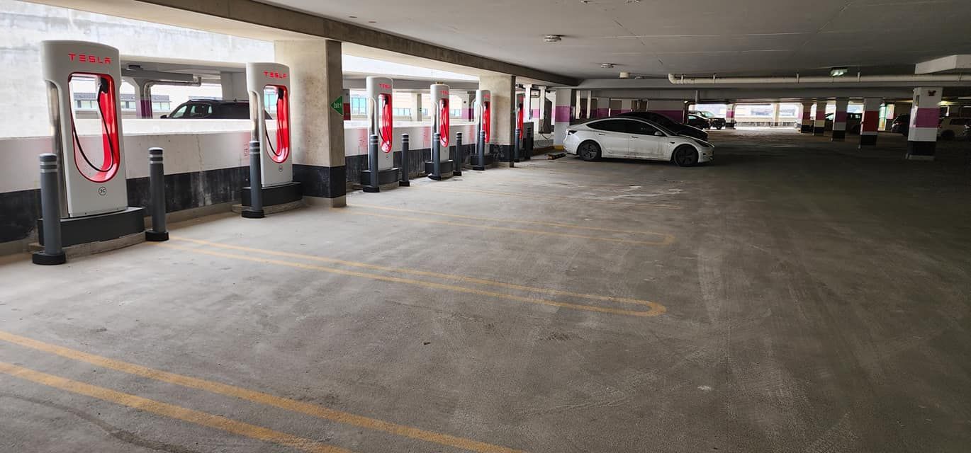 A parking garage filled with cars and charging stations.