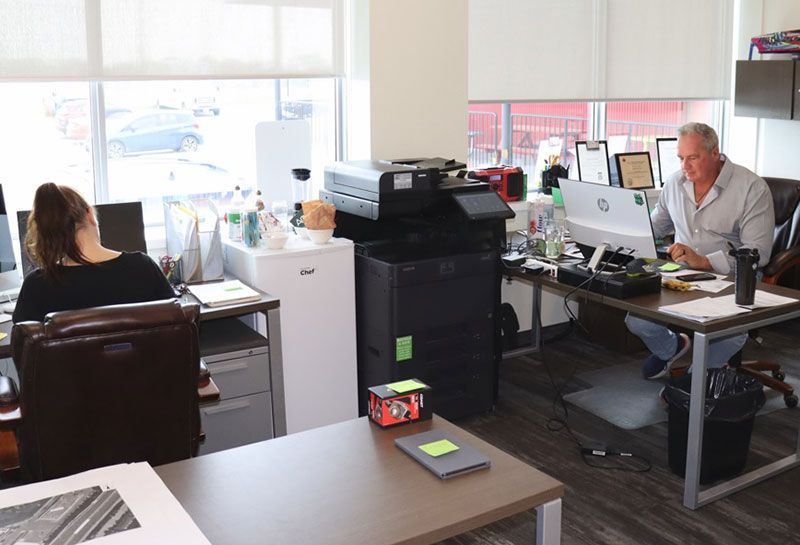 A man and a woman are sitting at desks in an office.